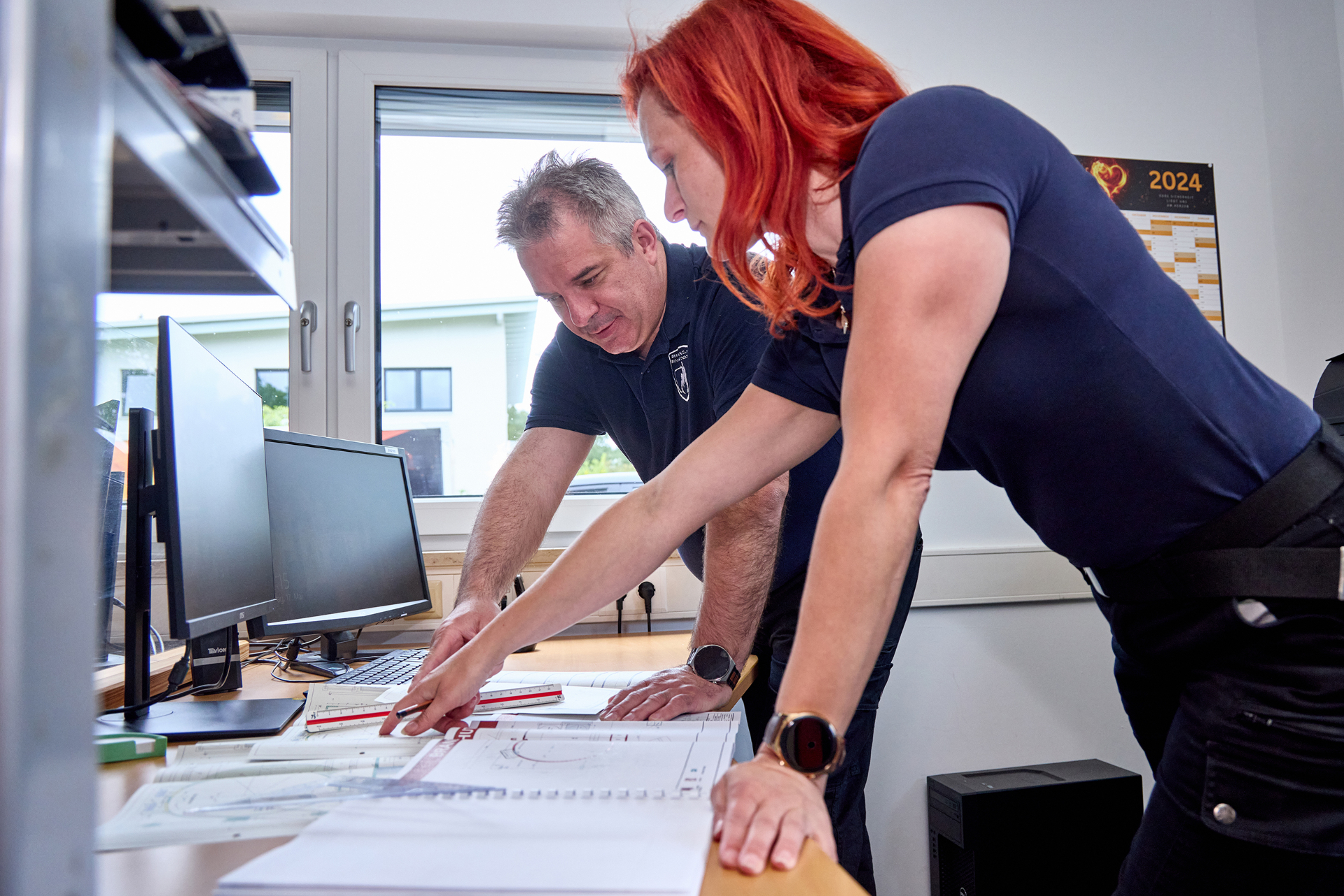 Brandschutzplanerin und Sachverständiger besprechen ein Brandschutzkonzept am Plan im Büro Greinwald